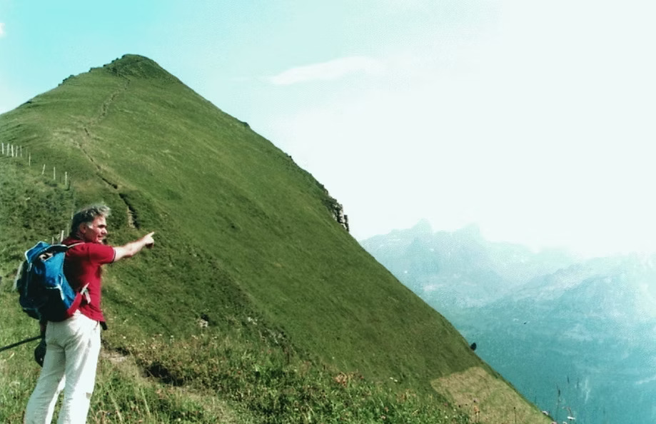 Professor Yaşargil pointing at Swiss Alps